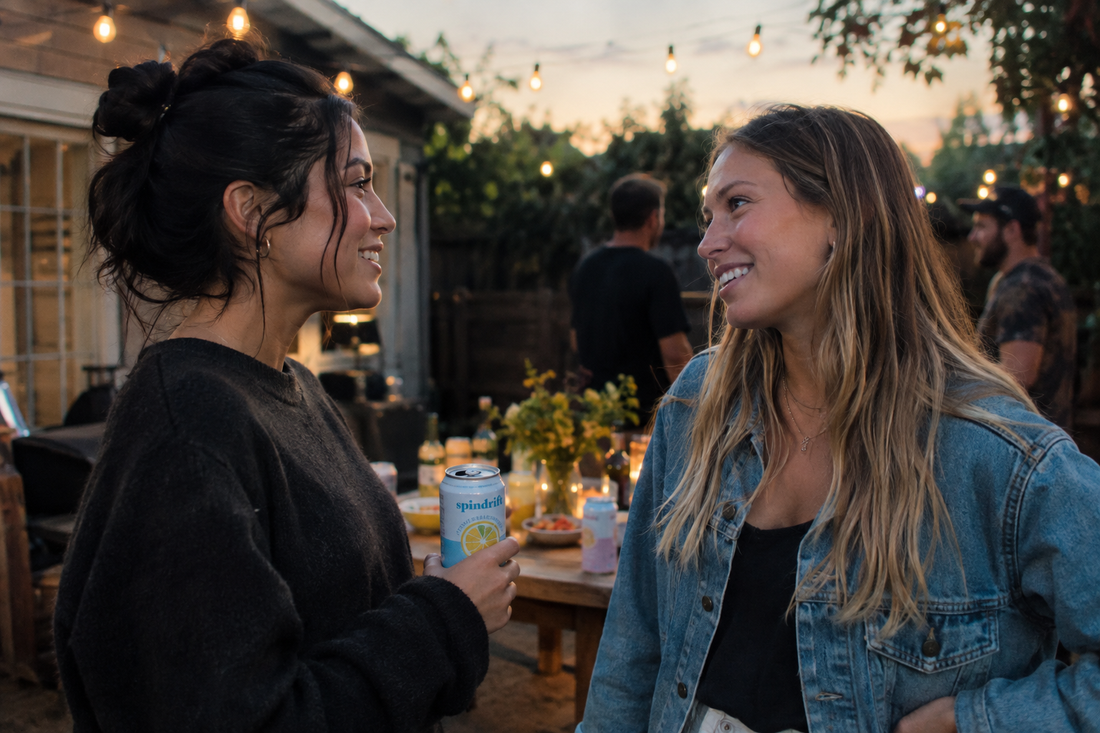 Two friends talking at a backyard party while one holds a sparkling water, confidently turning down a drink in sobriety